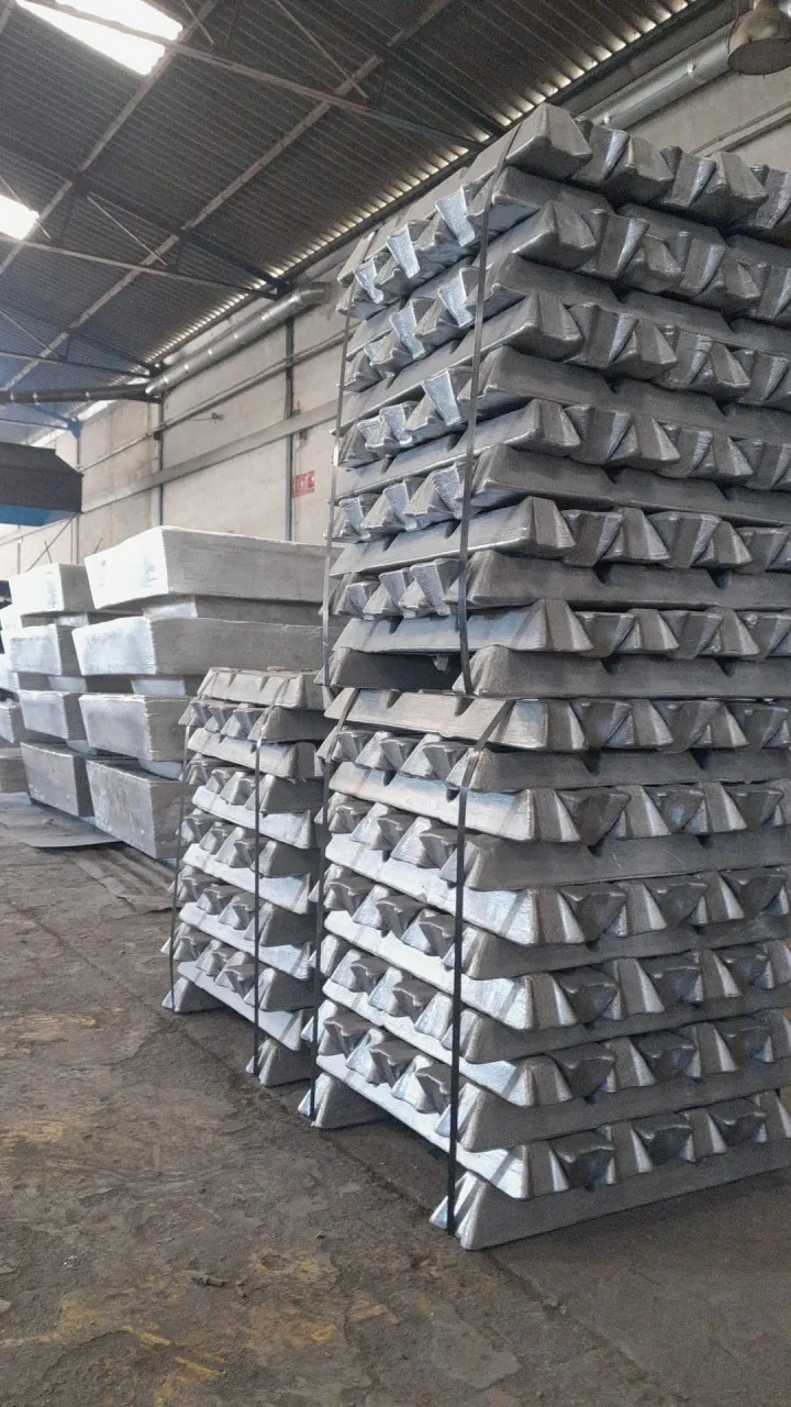 Palés de lingotes de aluminio atados con flejes en una nave industrial.